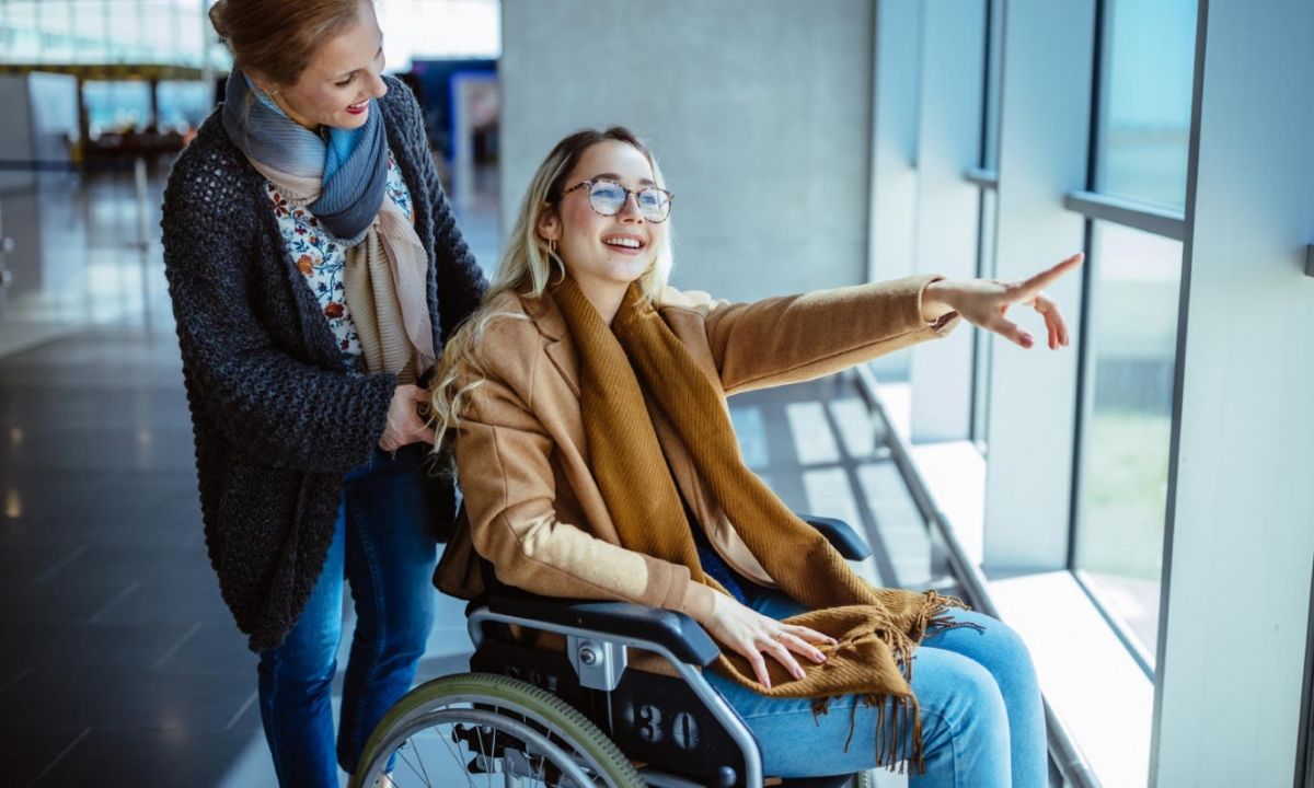 Frau im Rollstuhl mit Begleiterin am Flughafen von Ljubljana.